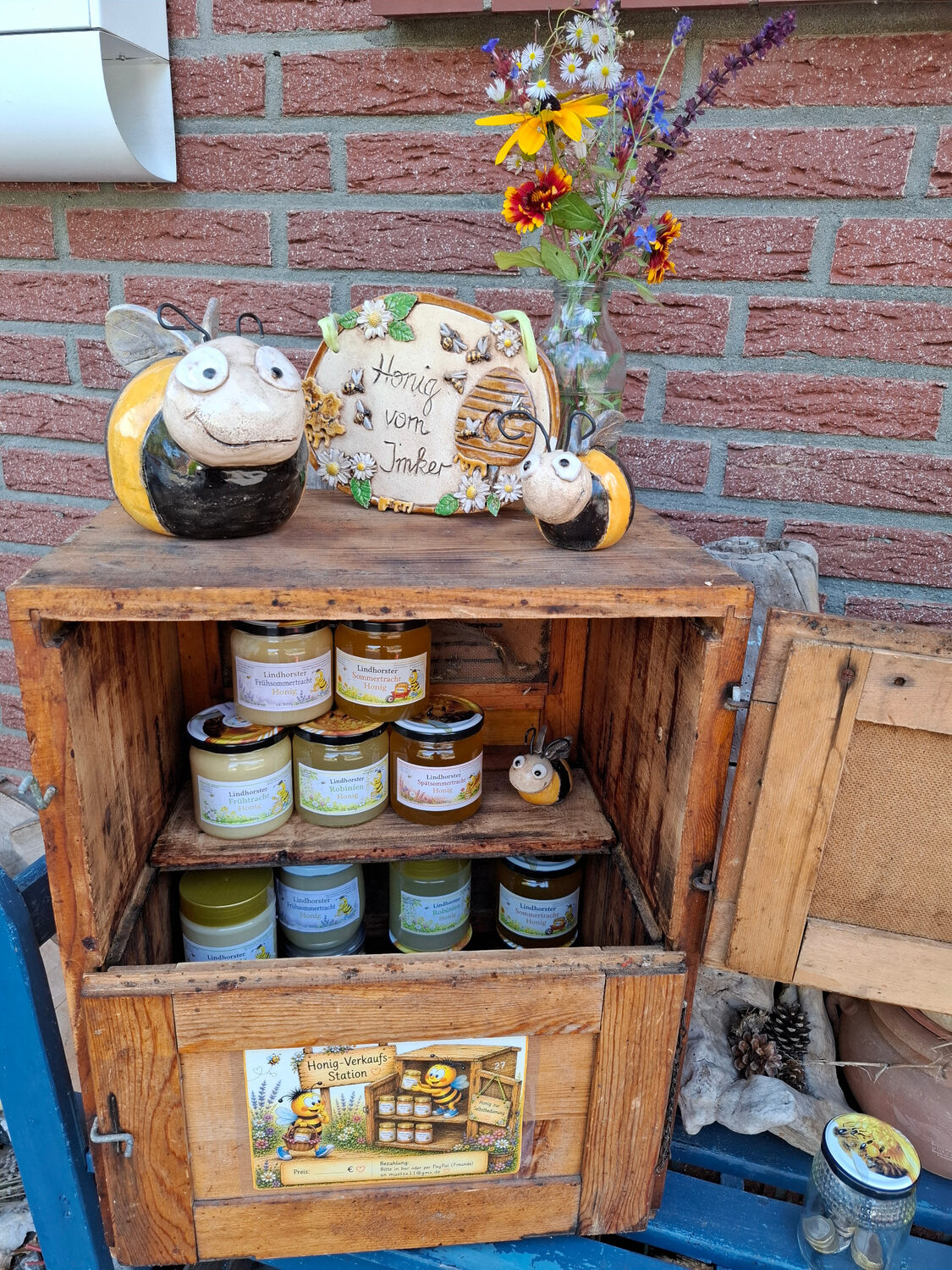 Unser Honigverkaufsstand in einer alten Bienenbeute mit Honiggläsern und Bienenfiguren vor der Haustür